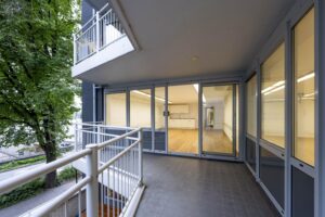 Balkon met glazen schuifdeuren en zicht op een leeg, modern interieur aan de Prins Hendrikkade.